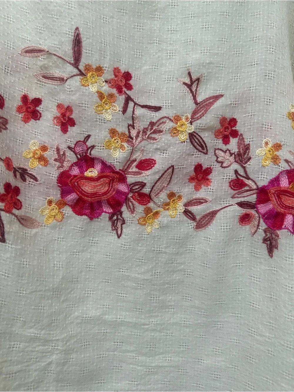 Soft cream cotton-mul feel poncho with vibrant pink, red floral embroidery.